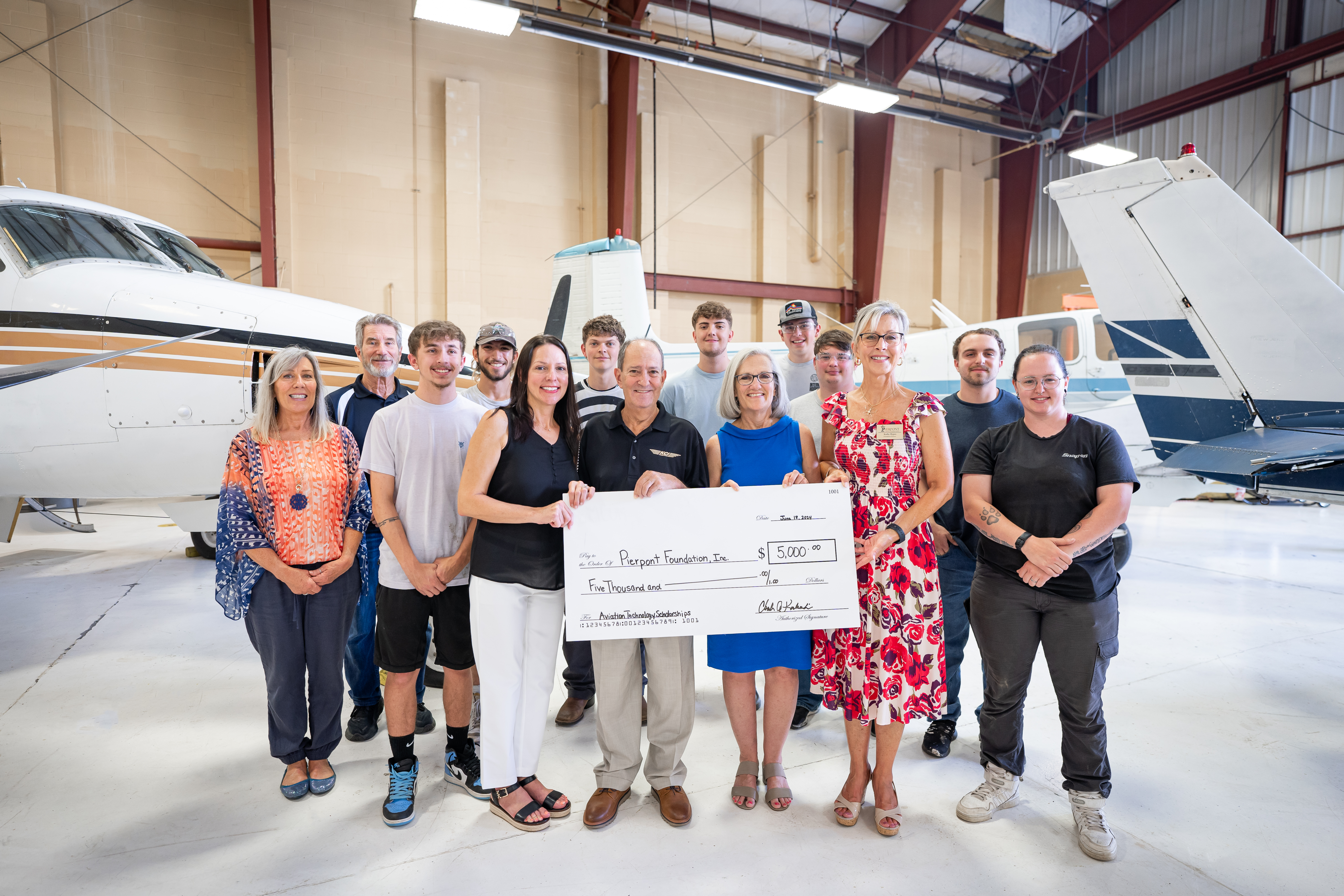 The Koukoulis Family is featured in the hangar with Pierpont faculty, staff, and students.