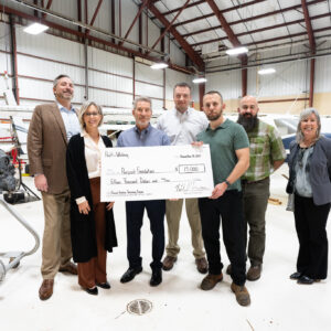 The group poses for a photo with the donation check.