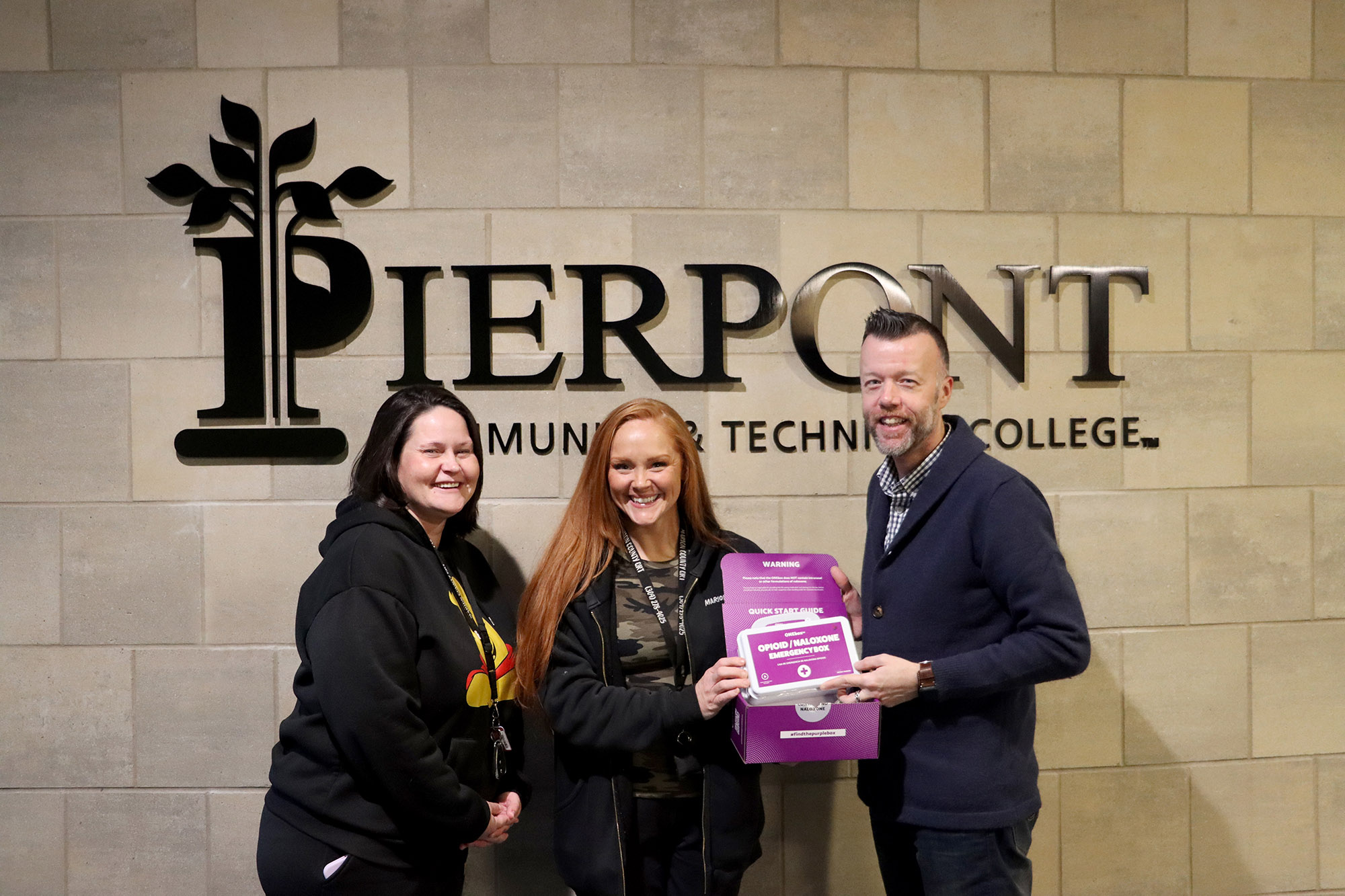 Brittany Miles and Malissa White of the Marion County Quick Response Team present a ONEbox emergency kit to Pierpont Interim President, Dr. Michael Waide.